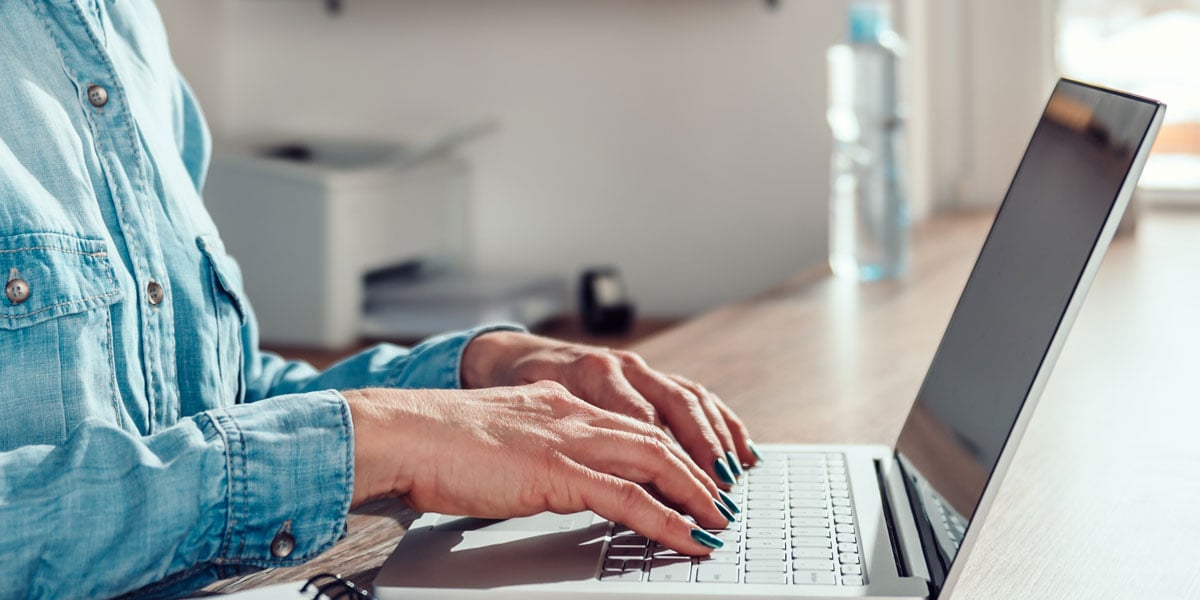 Female hands hovering over a laptops keyboard