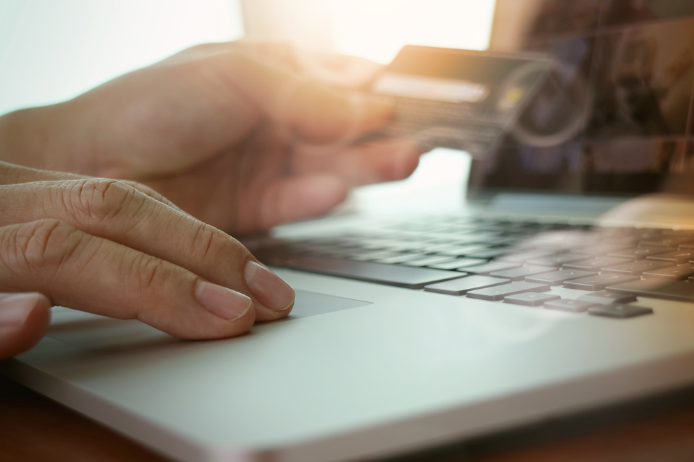 close up of hands using laptop and holding credit card  as Online shopping concept